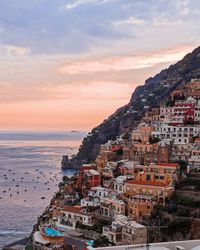 Townscape by sea against sky during sunset