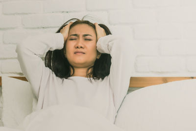 Portrait of a smiling young woman lying on wall