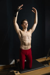 Shirtless man exercising against black background