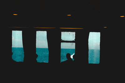 Silhouette man standing by window in sea