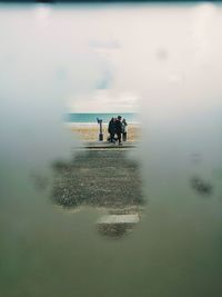 Rear view of men on beach against sky