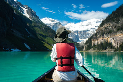 Rear view of woman sitting on boat in lake