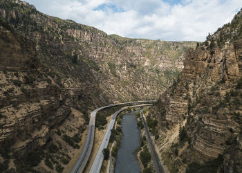 Aerial view of road and river amidst mountains against sky