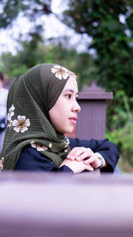 Profile view of woman wearing hijab looking away while sitting at park