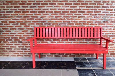 Empty bench against brick wall
