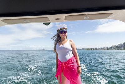 Portrait of young woman standing against sea