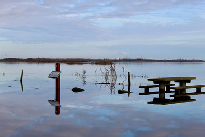 Wooden post in lake against sky