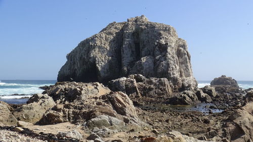 Rock formation on beach against clear sky