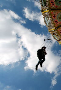 Low angle view of person on chain swing ride against sky