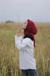 Side view of girl holding umbrella on field