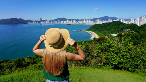 Panoramic view of traveler girl on viewpoint enjoying balneario camboriu skyline, brazil.