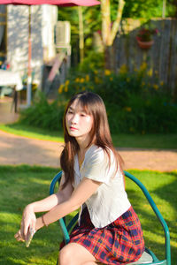 Portrait of smiling young woman standing against trees