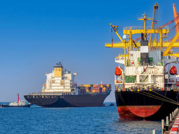 A tugboat pushing a container vessel during berthing at an industrial port.