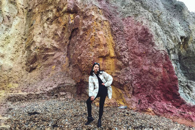 Portrait of woman standing against rock at beach