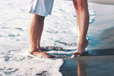 Low section of couple standing on beach