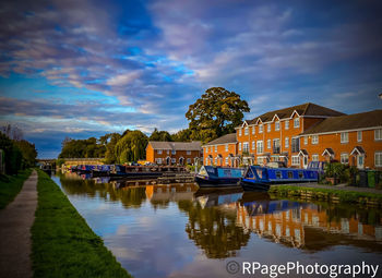 Boats moored on river by buildings in city against sky