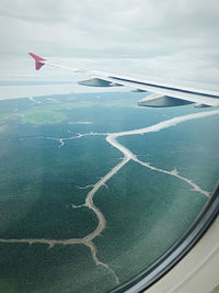 Aerial view of airplane flying over landscape against sky