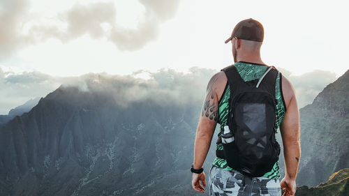 Rear view of man standing on mountain against sky