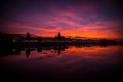 Reflection of illuminated buildings in water at sunset