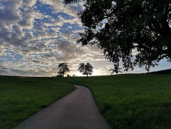 Road amidst field against sky