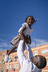 Father lifting daughter in front of building