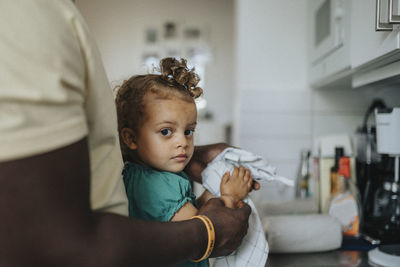 Father helping daughter dry hands with kitchen towel