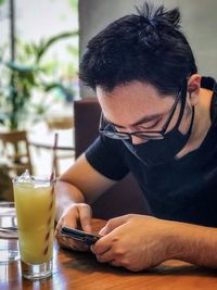 Midsection of man using mobile phone while sitting on table