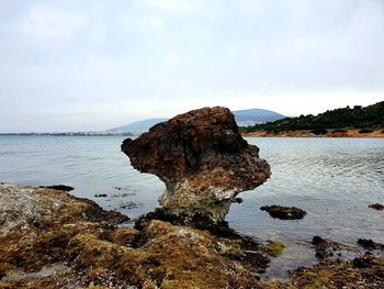 Rock formation on beach against sky