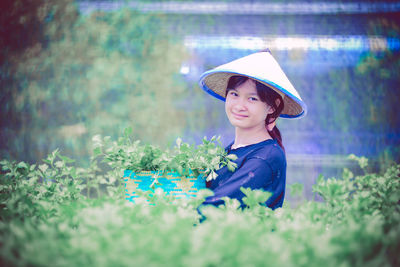 Portrait of young woman standing amidst plants