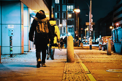 Rear view of woman walking on street at night