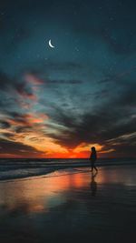 Silhouette woman walking at beach against cloudy sky