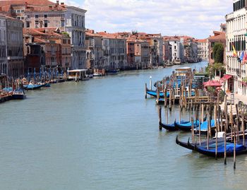 Boats moored on canal against buildings in city