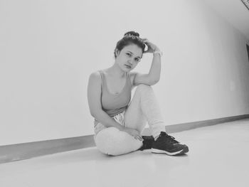 Portrait of woman sitting against wall at home