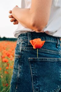 Red poppy in womans jeans pocket 