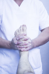 Midsection of doctor examining patient barefoot in hospital