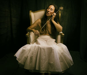 Woman in white skirt sitting in an antique armchair ii