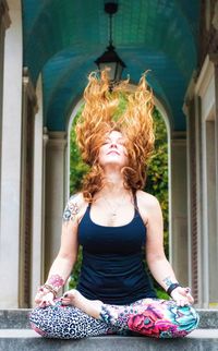 Full length of mature woman tossing hair while practicing yoga on steps