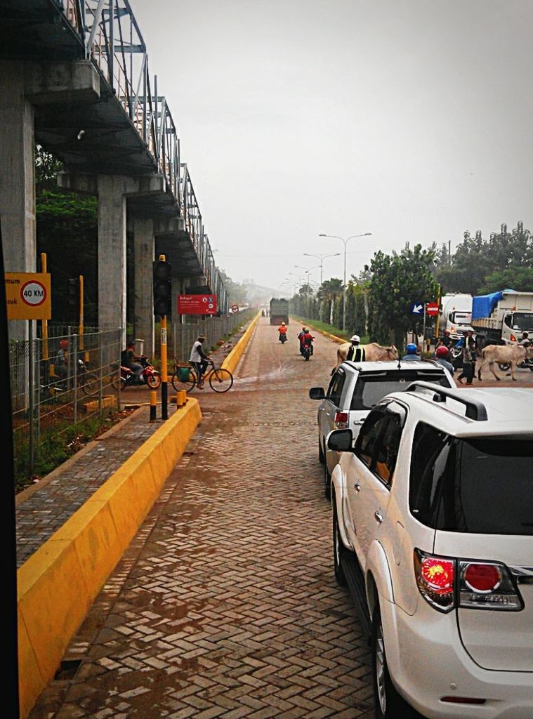 transportation, mode of transport, the way forward, built structure, architecture, diminishing perspective, railroad track, building exterior, vanishing point, land vehicle, car, city, clear sky, incidental people, public transportation, rail transportation, street, sky, road, outdoors