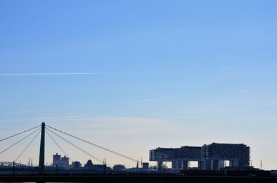 Suspension bridge and buildings against clear blue sky