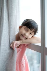 Portrait of girl standing by window at home