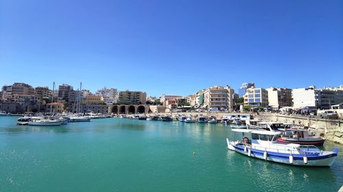 Boats in sea against clear blue sky