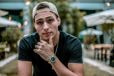 Portrait of young man wearing cap while sitting outdoors