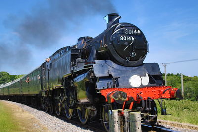 Steam train on railroad track against sky