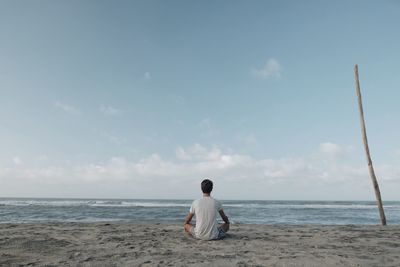 Rear view of man on beach against sky