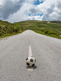 View of soccer ball on road against cloudy sky