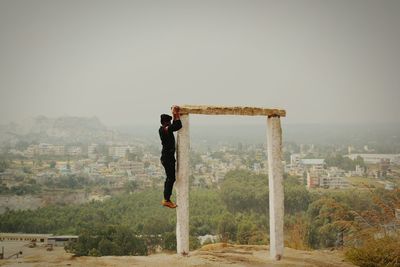 Side view of man climbing on pole