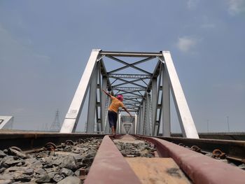 Low angle view of woman standing on bridge against sky