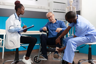 Doctor and nurse examining patient on wheelchair