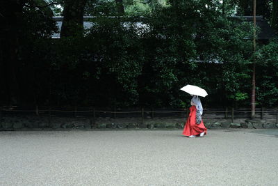 Rear view of woman walking with umbrella