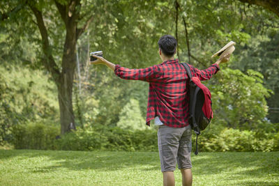 Full length rear view of man using mobile phone in park